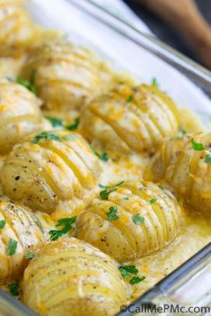 a glass casserole dish filled with potatoes and cheese, garnished with parsley