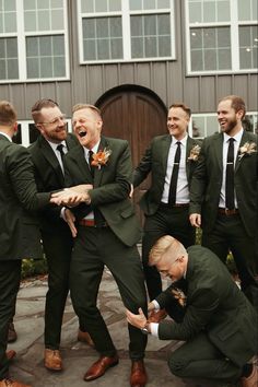 a group of men standing next to each other in front of a wooden door wearing suits and ties