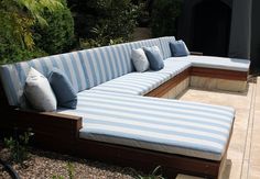 a blue and white striped couch sitting on top of a wooden bench next to plants