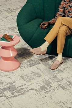 a man sitting on a green chair next to a pink table with a brown book