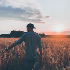 a man standing in a wheat field at sunset