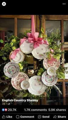 a wreath with pink bows and plates hanging from it