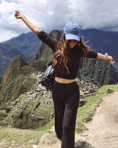 a woman standing on top of a mountain with her arms in the air