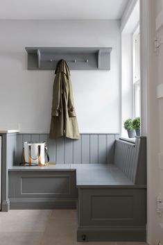 a coat rack and bench in a white room with gray paneling on the walls