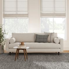 a living room scene with focus on the couch and coffee table in front of the window