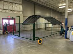 two people standing in front of a large caged area with tables and chairs around it