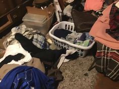 a messy room with clothes piled on top of each other and laundry in a basket