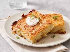 two pieces of french toast on a white plate with a glass of water in the background