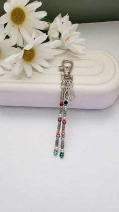 a pair of beaded keychains sitting on top of a white tray next to flowers