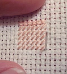 someone is stitching something on a piece of fabric with their thumbnails and fingers