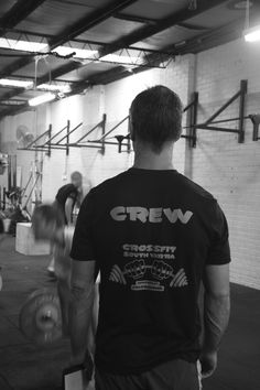 a man is standing in a gym with his back to the camera and looking at other people