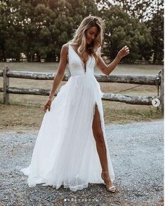 a woman in a white dress standing on gravel