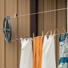 three towels hanging on a clothes line next to a brown building and an orange towel