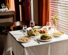 the table is set with food and wine for two people to enjoy it in front of the window