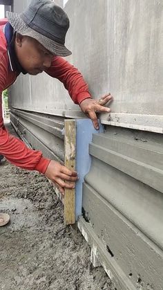 a man is working on the side of a building with cement and wood planks