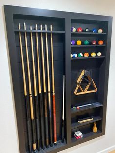 an entertainment center with pool cues, cues and other items on display in it