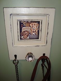 there is a picture frame on the wall with two puppies and a leash hanging from it