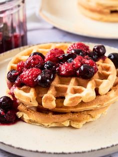 a stack of waffles topped with berries and blueberries on a white plate