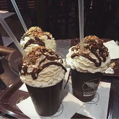 two ice cream sundaes sitting on top of a table