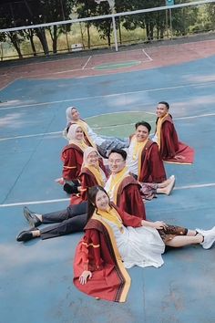 a group of young people sitting on top of a basketball court next to each other