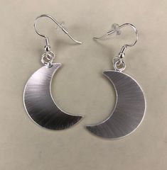 I've designed a pair of crescent moon earrings, 1 1/8 inches each in size, with dangling ear hook wires. The set is completely handmade in sterling silver. Inspired by Stevie Nicks, I wanted to fabricate matching earrings to the moon pendant and as this was for a customer request, I thought, what a grand idea! I can offer a 24K gold plating option that I will include in the drop down menu at checkout! The last image is to show the crescent moon necklace. Please convo for any questions! Allow me Modern Crescent Jewelry For Pierced Ears, Minimalist Silver Moon Phase Earrings, Modern Crescent Moon Charm Jewelry, Minimalist Moon Charm Drop Earrings, Modern Silver Crescent Earrings, Modern Crescent Jewelry With Ear Wire, Modern Crescent Sterling Silver Earrings, Adjustable Moon-shaped Minimalist Earrings, Modern Nickel-free Crescent Jewelry