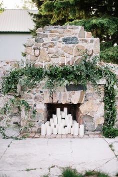 an outdoor fireplace with candles and greenery