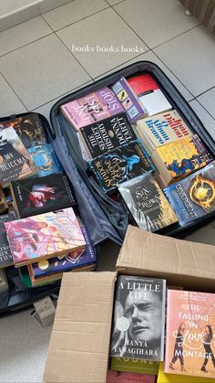 an open suitcase filled with books sitting on the floor next to a box full of books