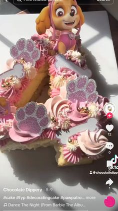 a pink and white cake with paw patrol decorations on it's top is shown