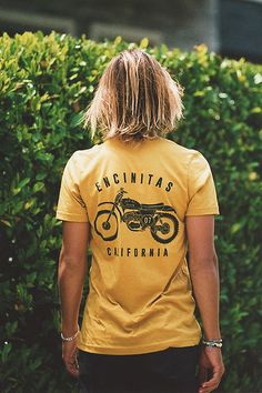 a person standing in front of bushes wearing a yellow shirt with the words encinita's california on it