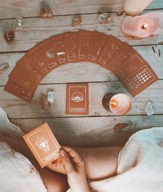 a person laying on the floor holding a card game in front of candles and other items