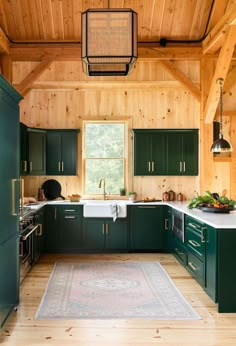 a kitchen with green cabinets and wooden walls