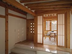 an open door leading to a dining room and living room with wood trimming on the walls