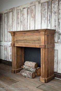 an old fireplace with wood logs stacked on the floor next to it and a wall behind it