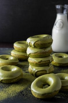 green donuts stacked on top of each other next to a bottle of milk