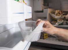 a person holding a plastic container in front of an open refrigerator