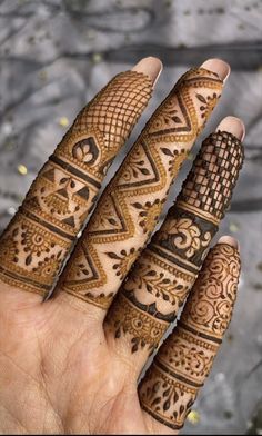 three henna tattoos on someone's hand, one is showing the intricate design