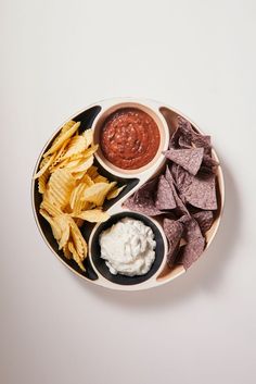 a plate with chips, guacamole and salsa