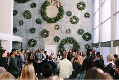 a large group of people standing in front of a wall with wreaths on it