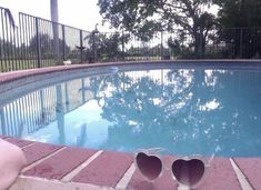 two pairs of sunglasses sitting on the edge of a swimming pool next to a person's feet