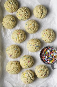 sprinkle cookies and a bowl of sprinkles on a sheet of wax paper