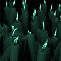 rows of lit candles with green and white flames