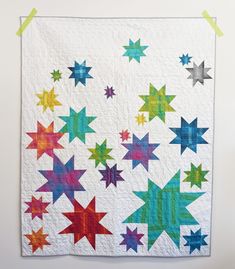 a quilted wall hanging with colorful stars on it