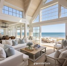 a living room filled with lots of white furniture next to an ocean front view window