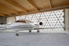 a small white plane parked inside of a building next to a wall with large windows