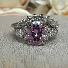 a close up of a ring with a pink diamond in it on a white cloth