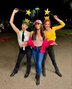 three women and one man are posing for the camera with their arms in the air