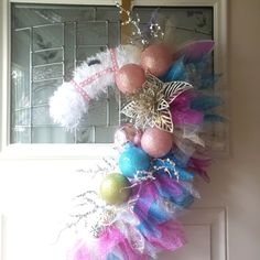 a wreath is hanging on the front door with feathers and other decorations around it,