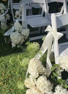 white chairs with bows and flowers in the grass