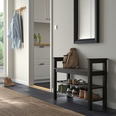 a white bench sitting under a mirror next to a coat rack with shoes on it