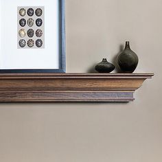 two vases sitting on top of a wooden shelf next to a framed photograph and artwork